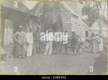 Dorfbewohner, Eine Gruppe von Dorfbewohnern, die vor einigen Häusern stehen. Teil des Fotoalbums Souvenir de Voyage (Teil 1), über das Leben der Familie Doijer in und um die Plantage Ma Retraite in Suriname in den Jahren 1906-1913., Hendrik Doijer (zugeschrieben), Suriname, 1906 - 1913, fotografische Unterstützung, Silbergelatine-Druck, Höhe 115 mm × Breite 166 mm Stockfoto