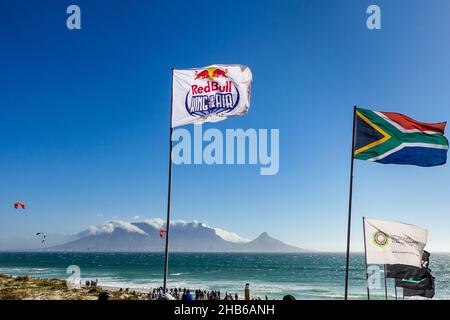 Red Bull-Flagge und andere Flaggen, die während des Red Bull King of the Air 2021 in Blouberg, Kapstadt, Südafrika, in der Luft fliegen Stockfoto