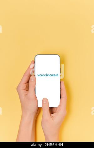 Weibliche Hände halten ein Telefon mit Aufschrift geimpft auf dem Bildschirm. Health Passport COVID-19 Stockfoto