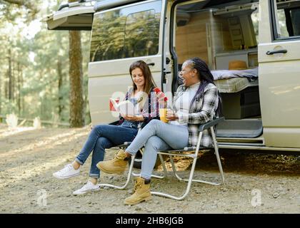 Multirassische Reisende Frauen in der Nähe von Wohnmobil im Wald Stockfoto