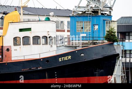 Bremerhaven, Deutschland. 17th Dez 2021. Am Bug des historischen Hafenschleppers Stier, der 1954 an der Jadewerft in Wilhelmshaven vor dem Deutschen Schifffahrtsmuseum an der Weser erbaut wurde, steht ein Weihnachtsbaum. Quelle: Hauke-Christian Dittrich/dpa/Alamy Live News Stockfoto