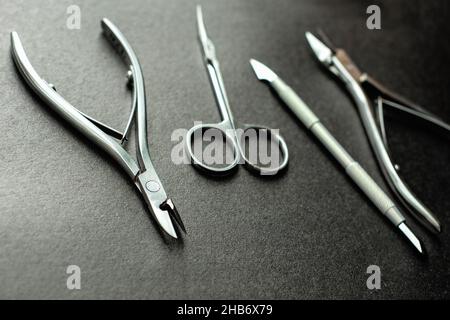 Set von Maniküre-Ausrüstung für die Nagelpflege auf schwarzem Hintergrund. Scheren, Zangen, Clipper, professionelle Werkzeuge für Meister, Schönheitssalons oder den Heimgebrauch. Stockfoto