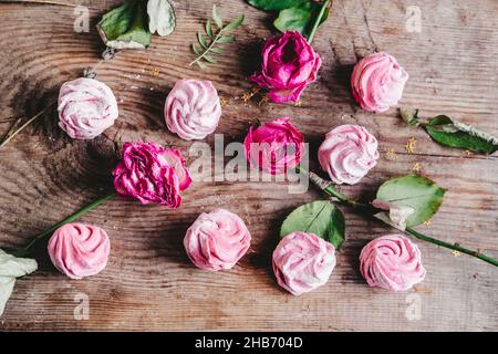 Verschiedene Beerenrosafarbene Sumpflaibe mit Rosenknospen, auf einem hölzernen Hintergrund. Do-it-yourself elastisch und weich marmelow Stockfoto