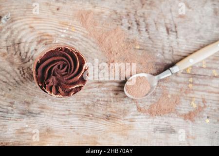 Schokoladenkuchen in einer Tasse auf einem hölzernen Hintergrund, Draufsicht. Kleinigkeit mit Schokoladencreme Stockfoto