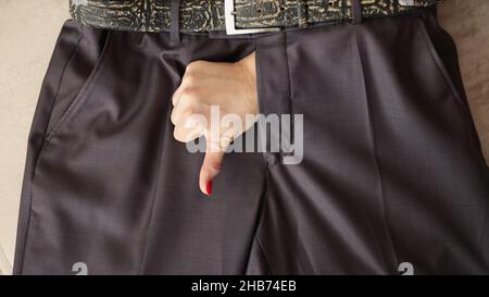 Frau zeigt Daumen nach unten Geste durch mans Hosen Stockfoto