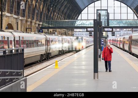 Passagier in roter Jacke, der ZUMA-Zug am King's Cross Bahnhof England verlässt Stockfoto