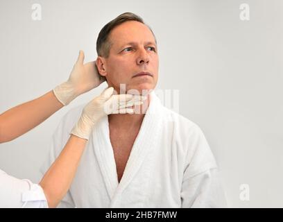 Schöner reifer kaukasischer Mann in weißem Frottee-Morgenmantel wird im Sanatorium, Wellness-Spa-Resort einer medizinischen Untersuchung unterzogen. Gesundheitswesen und Medizin Stockfoto