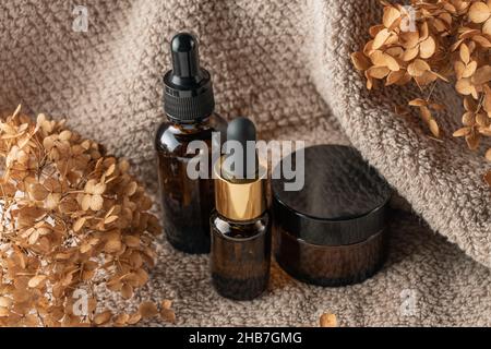 Set aus Kosmetikflaschen aus braunem Glas auf braunem Hintergrund. Naturkosmetik ohne Markenverpackung Stockfoto