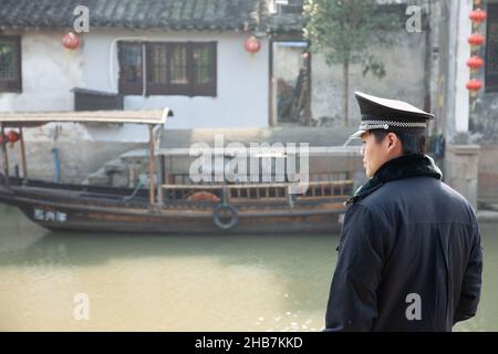 Polizist beobachtet den Verkehr auf einem Kanal im Wasserdorf Xitang, China Stockfoto