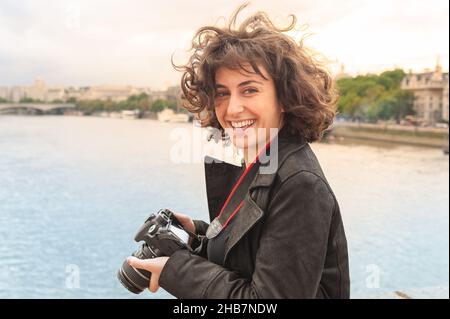 Attraktive, glückliche, junge, weibliche Touristen aus London fotografieren den Blick über die Themse auf einer Stadtrundfahrt Stockfoto