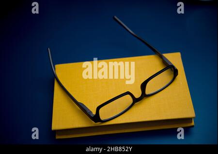 Gelbes Buch und Lesebrille Stockfoto