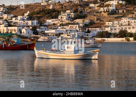 Griechisches Fischerboot im alten Hafen der Insel Mykonos, Hintergrund von weißen Chora-Gebäuden. Kykladen, Griechenland. Traditionelle Boote ankerten auf ruhigem Meerwasser bei Stockfoto