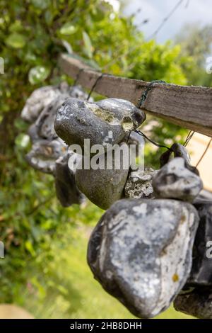 Im Sommer hängen Steine oder Hühnergötter an einem Seil an der frischen Luft Stockfoto