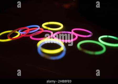 Bunte LED-Ringe leuchten auf dem schwarzen Hintergrund. Leuchtende Ringe in grün, rosa, rot, gelb, blau. Partyzubehör. Kinderspielzeug Stockfoto