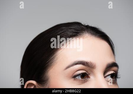 Beschnittene Ansicht des jungen Models mit braunem Haar isoliert auf grau Stockfoto