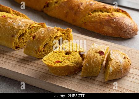 Frisch gebackenes, hausgemachtes Baguette mit Gewürzen aus der Nähe von einem hölzernen Schneidebrett Stockfoto