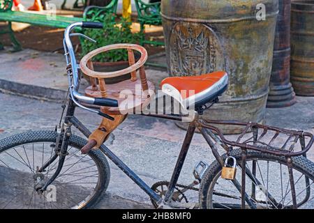 Selbstgemachter Kindersitz aus Holz, montiert auf einem alten rostigen Fahrrad in Kuba Stockfoto