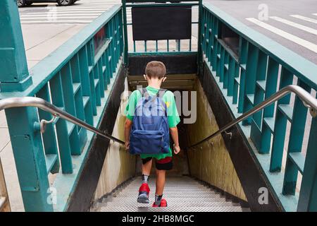 USA, New York, New York City, Rückansicht eines Jungen (8-9) mit Rucksack, der auf dem Weg zur Schule in die U-Bahn fährt Stockfoto