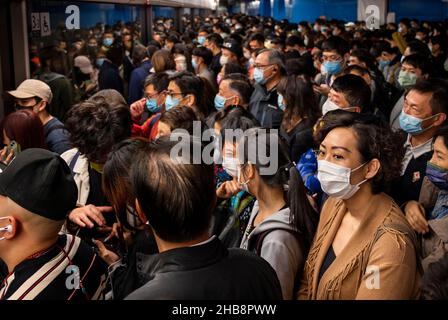 Pendler mit Gesichtsmasken werden gesehen, wie sie auf eine U-Bahn warten, die an einer MTR-Station in Hongkong ankommt. Die Stadt Hongkong ist in Alarmbereitschaft, da eine stark mutierte neue Covid-19-Variante, die als Omicron-Variante bekannt ist, von einem Passagier aus Südafrika entdeckt wurde. Stockfoto