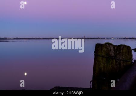 Angus, Großbritannien. 17th Dez 2021. UK Weather, Montrose Basin, Angus, Scotland, UK 17th of Dec 2021: Im Bild - das Montrose Basin in Angus, während die Sonnenuntergänge und der Mond seinen Platz einnehmen, was zu einem dramatischen Himmel voller Farben führt, da die Temperatur heute Abend in Montrose auf -1 sinkt. Kredit: Barry Nixon/Alamy Live Nachrichten/Alamy Live Nachrichten Stockfoto