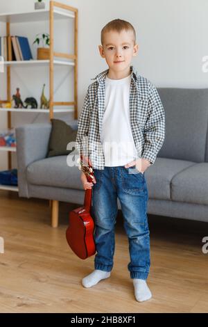 Talentiertes Kind mit Sopranukulele zu Hause. Vorschuljunge, der in Ruhe Gitarre lernt. Konzept der frühkindlichen Bildung und Musikhobby Stockfoto