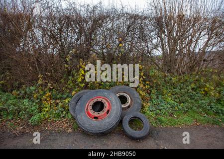 Weggeworfene und gedumpte Reifen lagen in einer Hecke auf einer Landstraße in Worcestershire und verursachten einen Augenaufdruck und mögliche zukünftige Umweltverschmutzung. Stockfoto