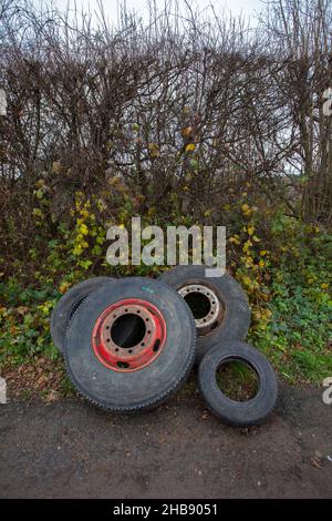 Weggeworfene und gedumpte Reifen lagen in einer Hecke auf einer Landstraße in Worcestershire und verursachten einen Augenaufdruck und mögliche zukünftige Umweltverschmutzung. Stockfoto