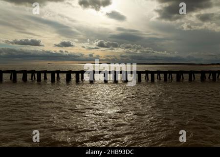 Dramatischer Blick auf das Meer des Southwold Hafeneingangs in der Abenddämmerung, der den Anlegesteg in Walberswick nach Süden zeigt. Stockfoto