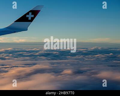 Flugansicht mit Logo der Schweizer Fluggesellschaft auf dem Flugzeugflügel bei Sonnenuntergang. Stockfoto