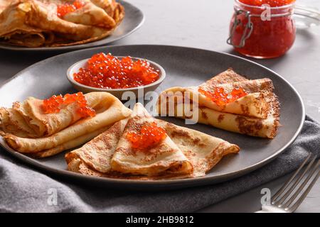 Russische dünne Pfannkuchen mit rotem Kaviar auf grau. Traditionelle Religion Frühstück für nationale Feiertag Fasching. Maslenitsa. Nahaufnahme. Stockfoto