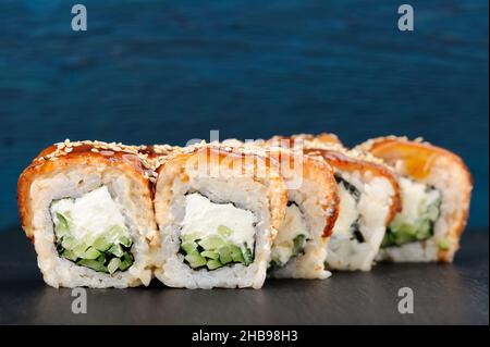 Leckere Sushi-Rollen mit Frischkäse, Nori und Gurke, bedeckt mit Aal und Karamellsauce Copyspace Stockfoto