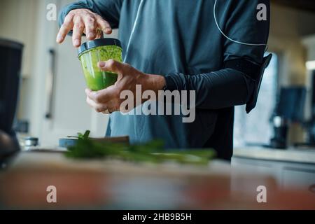 Älterer Mann, der nach einem Lauf in seiner Küche einen Smoothie zubereitet Stockfoto