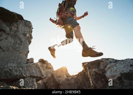 Mann mit einem prothetischen Bein, der von Felsen springt Stockfoto