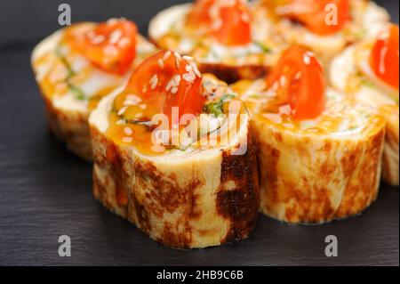 Set aus japanischen Brötchen mit Omelett und Tomaten auf schwarzem Teller Stockfoto