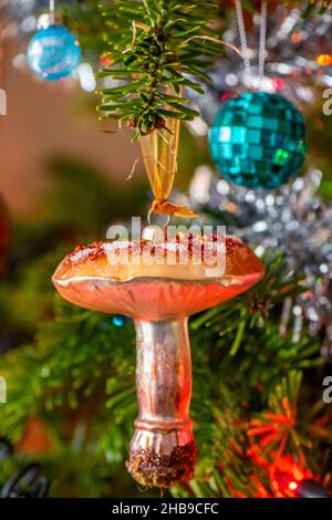 Funkelnde weihnachtsdekoration in Form eines Pilzpilzes, festliche Weihnachtsdekorationen auf einem weihnachtsbaum mit Lametta und Kugeln. Stockfoto