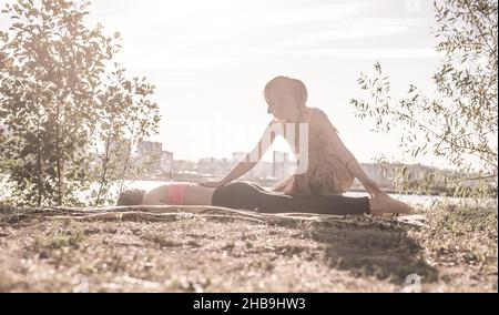 Massagetherapeutin wendet ihre Massagefähigkeiten auf ihren Klienten auf dem Gras an. Stockfoto