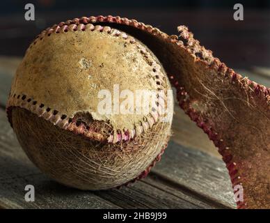 Zerfetzter Baseballschläger auf Holz mit Ziernähten und Innenleben des Baseballs Stockfoto