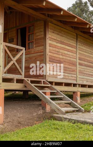 Rustikale Holzhütte mit Balkon und Treppe, Detail der Fassade, Struktur auf dem Feld, Lifestyle am Tag Stockfoto