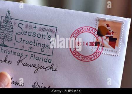 Orlando, Usa. 17th Dez 2021. Auf dieser Fotolabbildung ist eine Weihnachtskarte in Orlando zu sehen, die einen Poststempel aus dem nahegelegenen Weihnachts-, Florida-Postamt trägt. Jedes Jahr bringen Tausende von Menschen ihre Weihnachtskarten zur winzigen Post in Weihnachten, Florida, um sie mit dem einzigartigen Weihnachtsstempel stempeln zu lassen. Postkunden können auch von der Post bereitgestellte Gummistempel verwenden, um ihre Umschläge mit saisonalen Designs und Begrüßungen zu schmücken. Kredit: SOPA Images Limited/Alamy Live Nachrichten Stockfoto