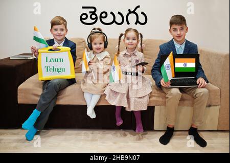 Vier Kinder zeigen Inschrift lernen telugu. Fremdsprachenlernkonzept. Indische Flaggen. Stockfoto