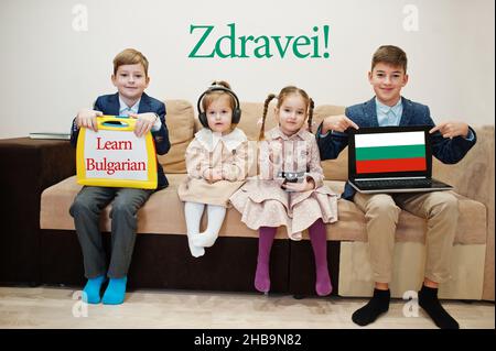 Vier Kinder zeigen die Inschrift bulgarisch lernen. Fremdsprachenlernkonzept. Zdravei! Stockfoto