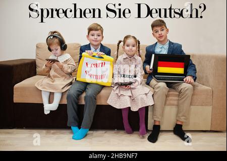 Vier Kinder zeigen die Inschrift Deutsch lernen. Fremdsprachenlernkonzept. Sagen sie Deutsch? Stockfoto
