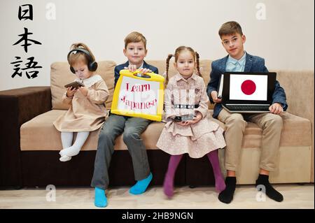 Vier Kinder zeigen die Inschrift Japanisch lernen. Fremdsprachenlernkonzept. Stockfoto