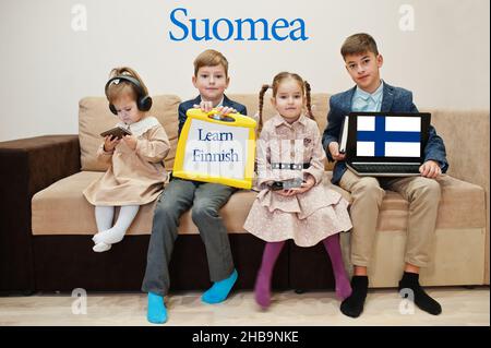 Vier Kinder zeigen die Inschrift finnisch lernen. Fremdsprachenlernkonzept. Suomea. Stockfoto