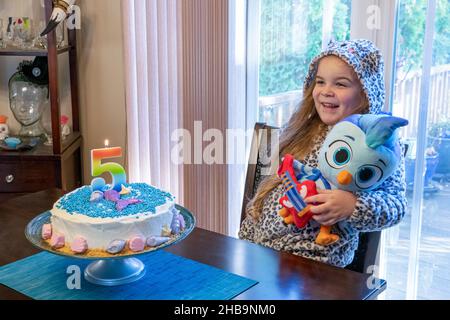 Lynwood, Washington, USA. Lily an ihrem fünften Geburtstag mit einem Do Re me Spielzeug und ihrem Geburtstagskuchen Stockfoto