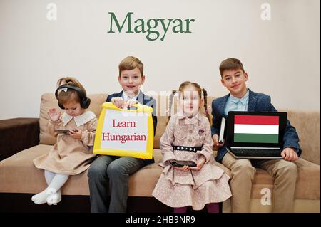 Vier Kinder zeigen die Inschrift ungarisch lernen. Fremdsprachenlernkonzept. Magyar. Stockfoto