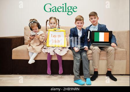Vier Kinder zeigen die Inschrift irisch lernen. Fremdsprachenlernkonzept. Gaeilge. Stockfoto