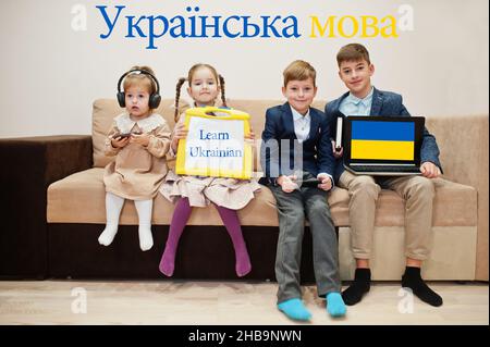 Vier Kinder zeigen die Inschrift ukrainisch lernen. Fremdsprachenlernkonzept. Stockfoto