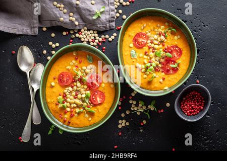 Grüne Linsensuppe mit Kirschtomaten und Rahm. Gelbe Linsensuppe aus Gemüse. Stockfoto