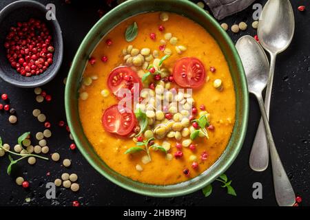 Gesunde Linsensuppe mit Kirschtomaten und Rahm. Gelbe Linsensuppe aus Gemüse. Stockfoto